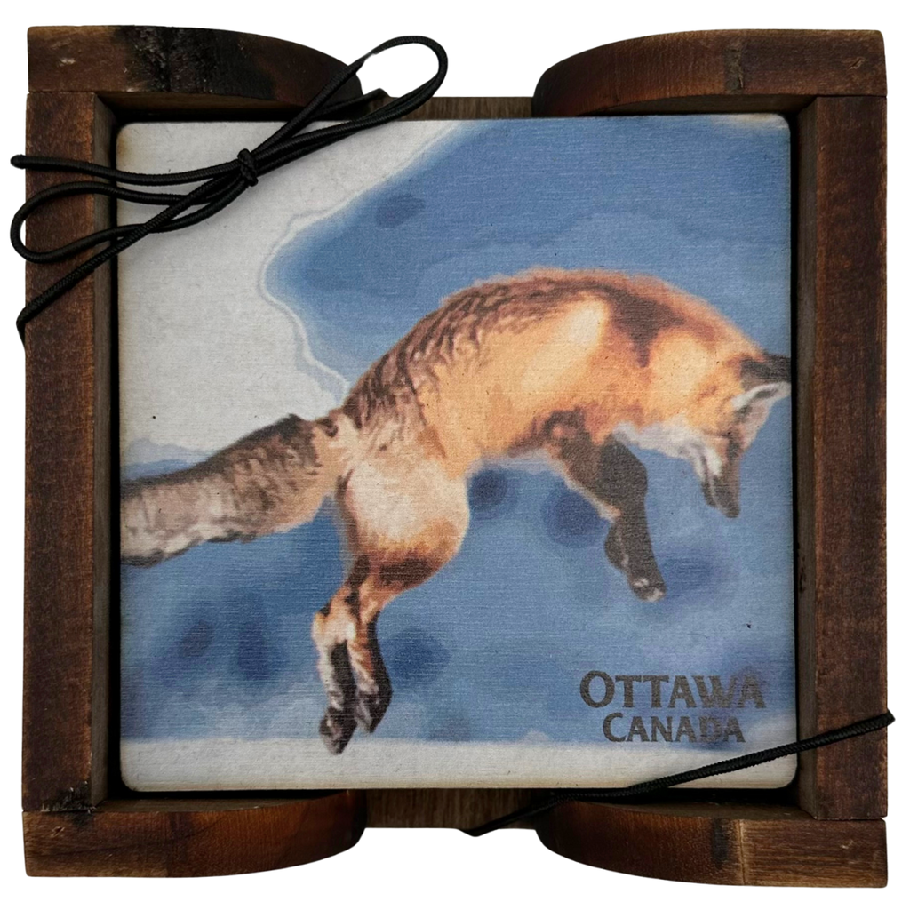 A square wooden coaster displayed in an attractive wooden holder. The coaster shows a leaping red fox depicted against a blue sky. The coaster says "Ottawa Canada" in the bottom right, beneath the fox.