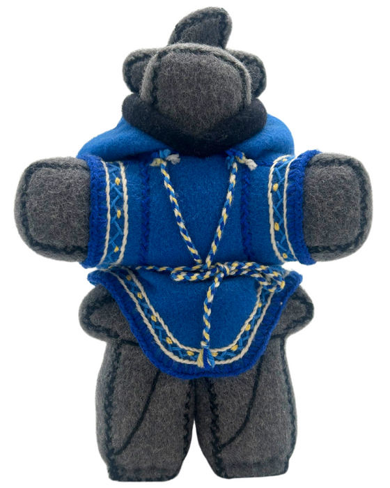 A hand-stitched felt doll made of grey felt in the shape of an inukshuk wearing a blue parka with embroidered yellow trim. The inukshuk carries a smaller inukshuk on its back.