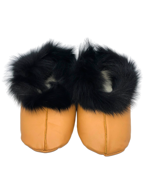 A pair of beige sealskin slippers with black fur around the entrance and white insides.