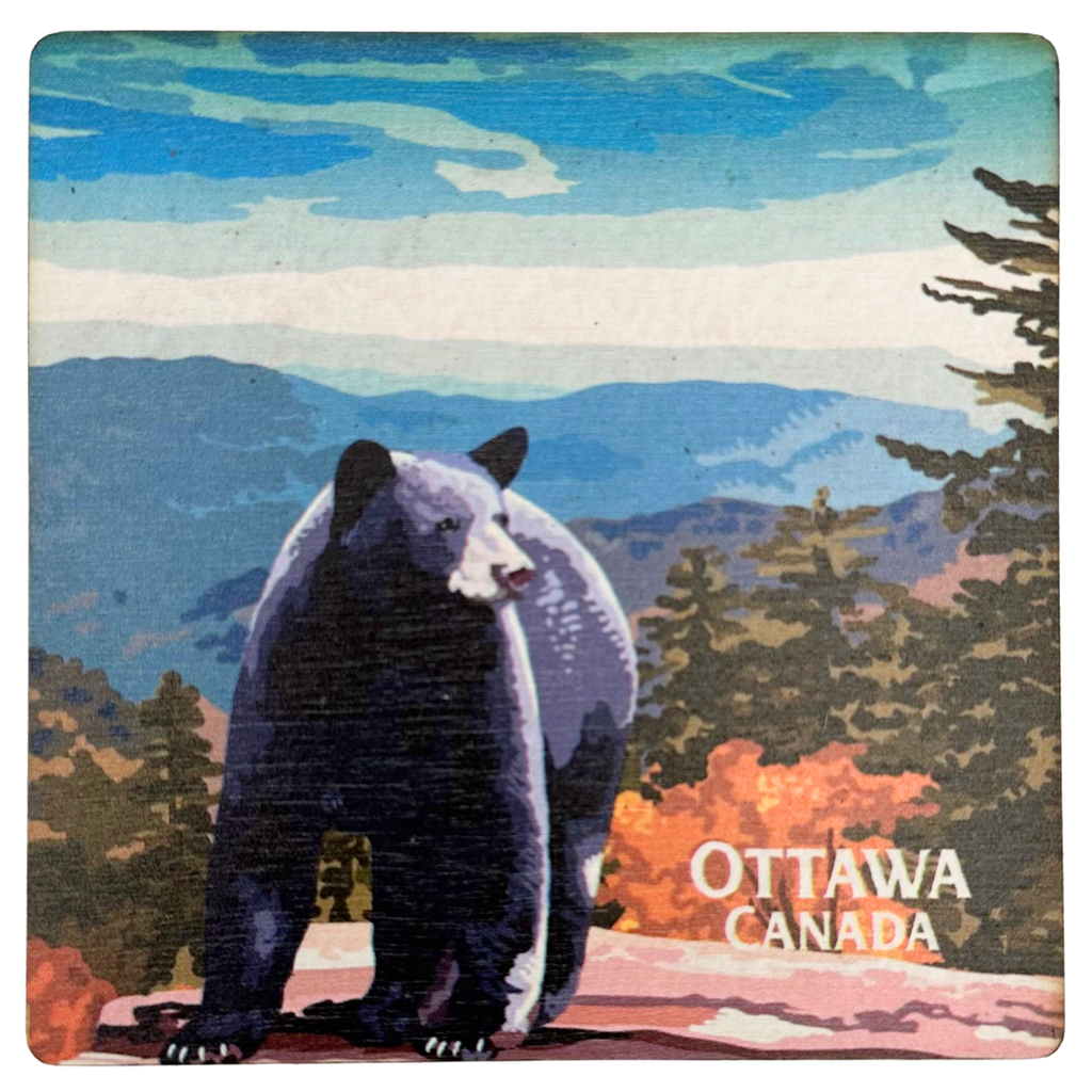 A square wooden coaster with a black bear standing on a rock against a background of forest, mountains, and blue sky. In the bottom right, the coaster reads "Ottawa Canada"