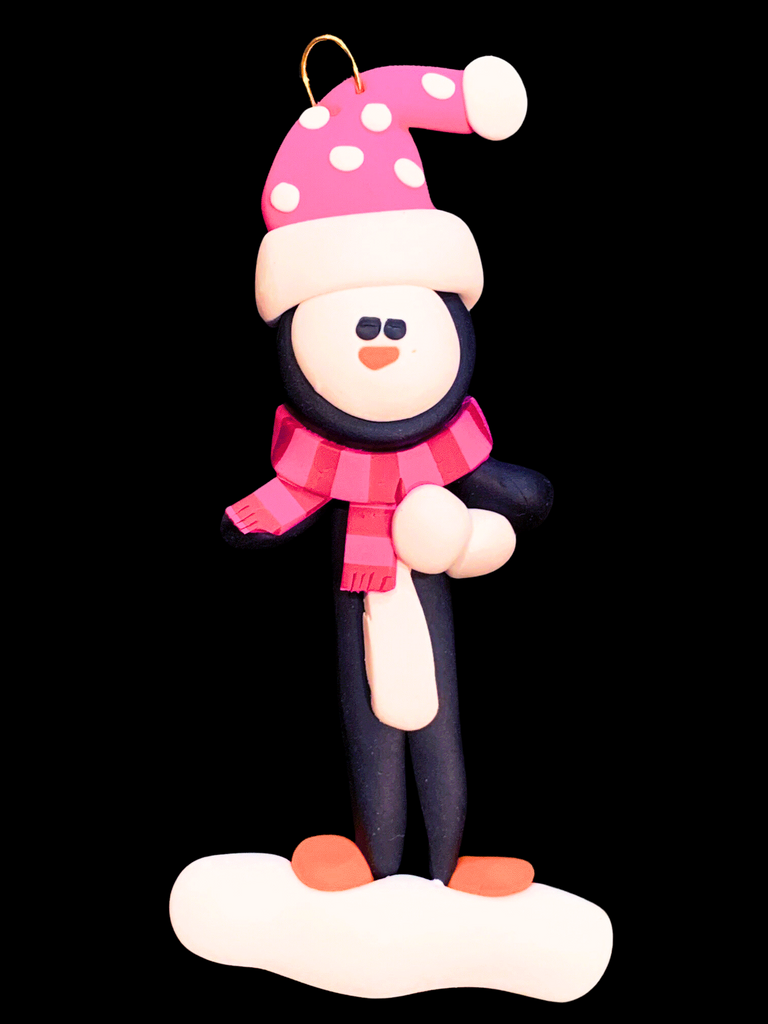 Black and white penguin with a pink polka dot Santa hat and a pink and dark pink striped scarf