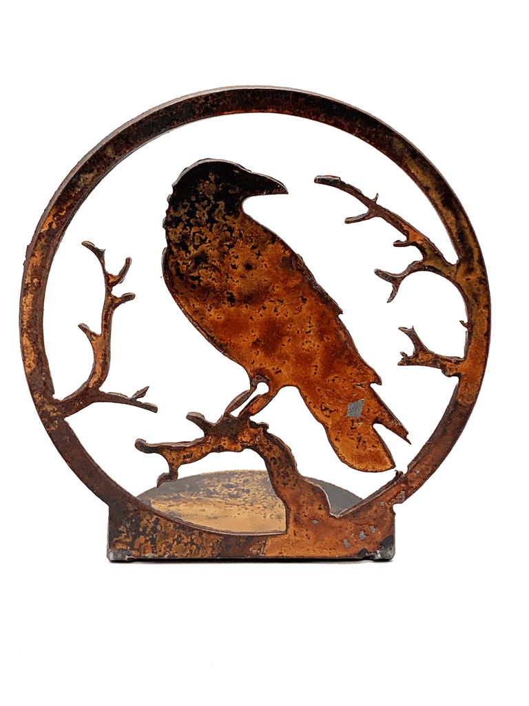 This candle holder depicts a crow perching on a branch as it looks over its shoulder. The scene is cut from sheet steel and then oxidised to a tasteful red patina.