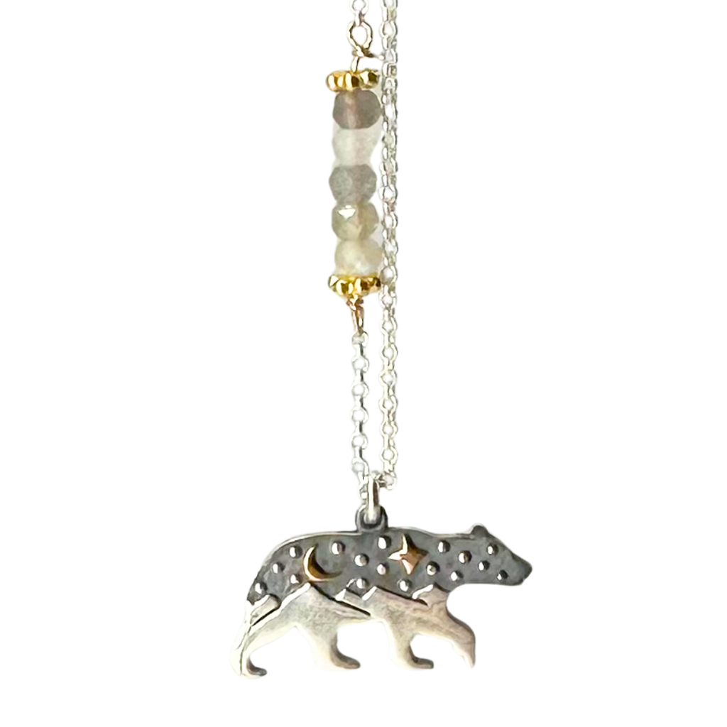 Silver chain with 5 coloured beads in middle of chain attached with gold chain links that look like flowers. Pendant is a bear with legs that turn into mountain peaks. The upper body of the bear resembles a night sky with a gold cresent moon and a gold 4-point star. Small silver dots are also on the upper body of the bear.