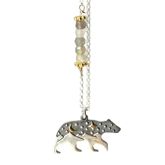 Silver chain with 5 coloured beads in middle of chain attached with gold chain links that look like flowers. Pendant is a bear with legs that turn into mountain peaks. The upper body of the bear resembles a night sky with a gold cresent moon and a gold 4-point star. Small silver dots are also on the upper body of the bear.