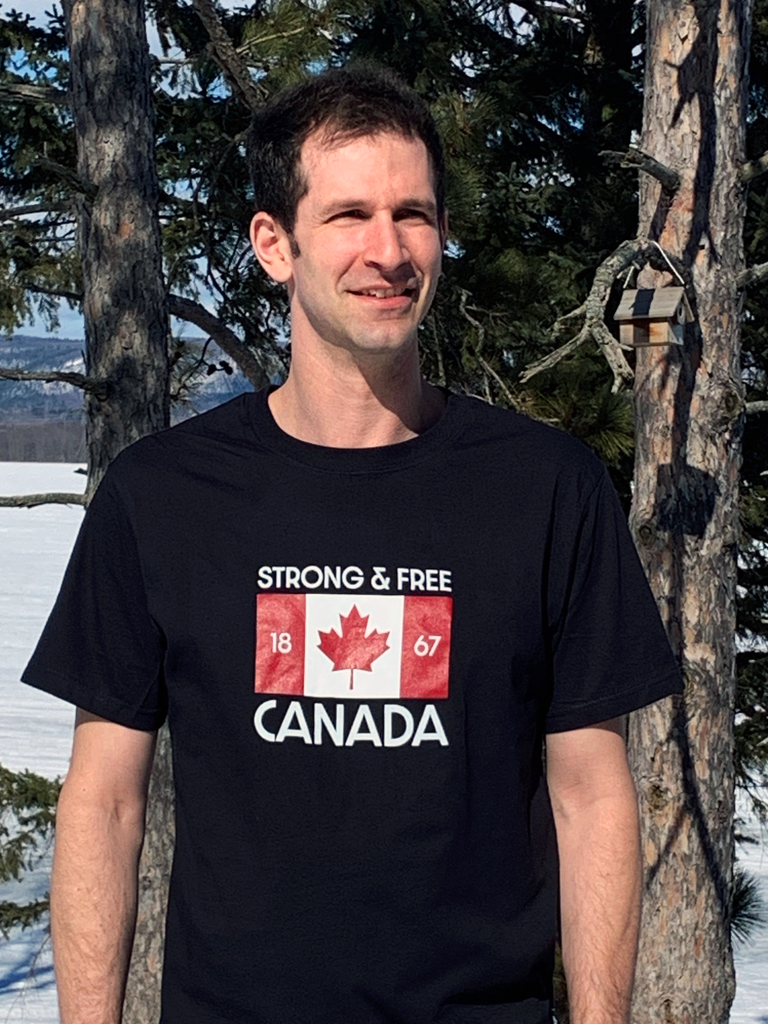 Black unisex tee shirt with a Canadian flag with 1867 flanking the maple leaf and the words STRONG & FREE above and CANADA below