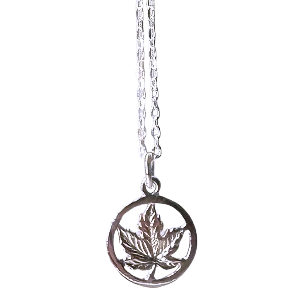 A small sterling silver maple leaf on a silver chain sits on a black background. The maple leaf is enclosed by a silver circle. The chain attaches to the top of the circle.