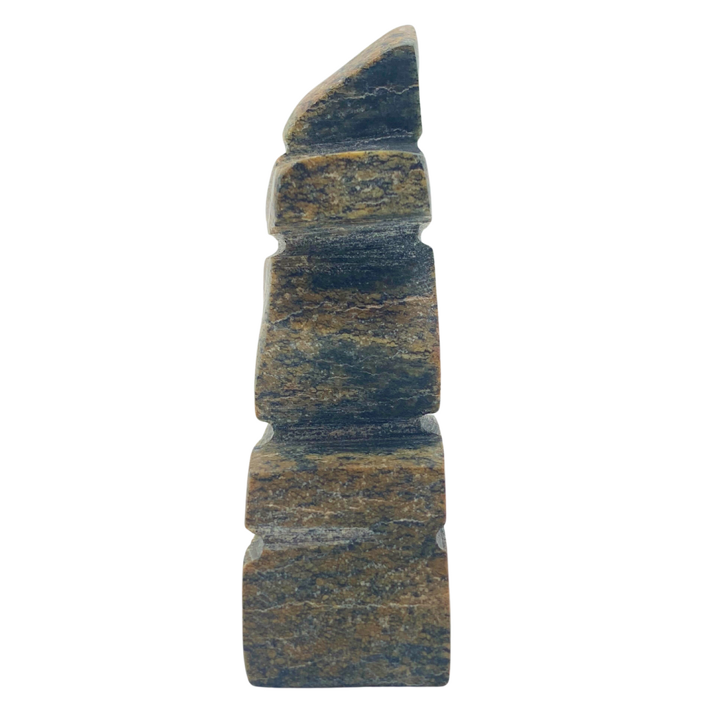 A human-shaped inukshuk sculpture, approximately 3 inches high. The stone is mottled black and brown soapstone.