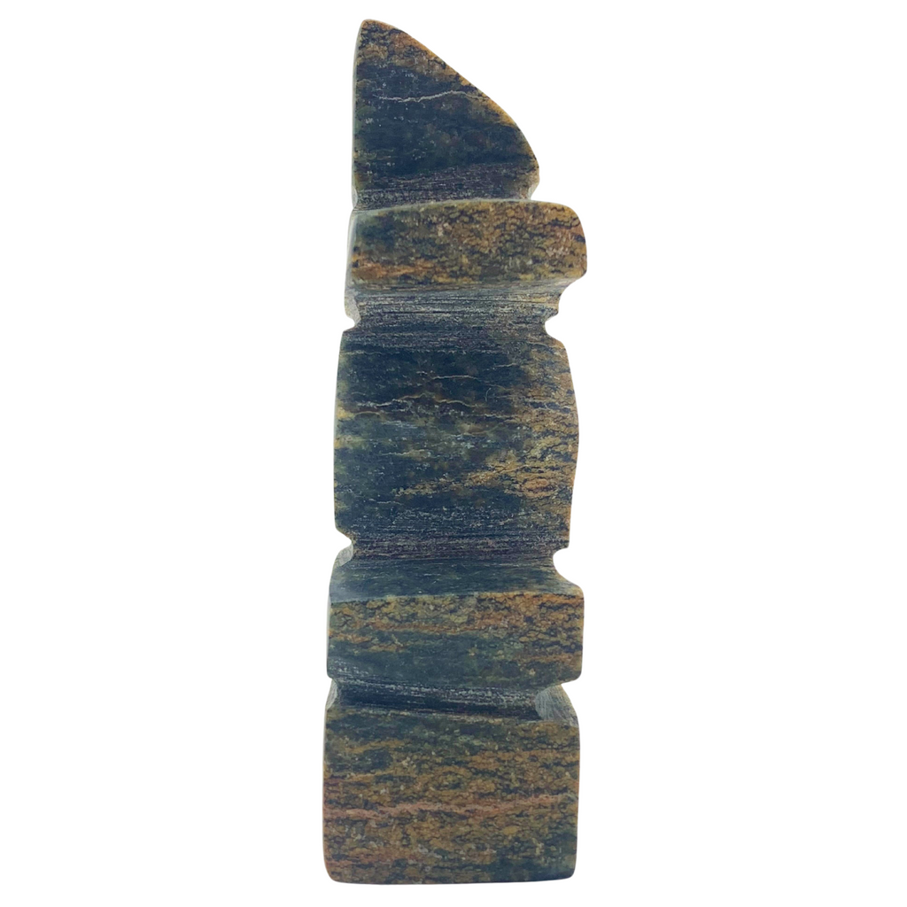 A human-shaped inukshuk sculpture, approximately 3 inches high. The stone is mottled black and brown soapstone.