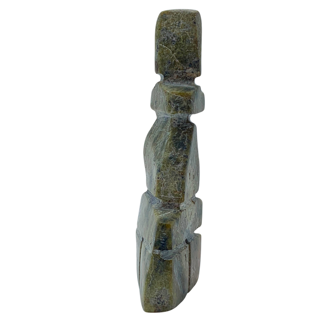 A human-shaped inukshuk sculpture, approximately 4 inches high. The stone is mottled black and green soapstone.