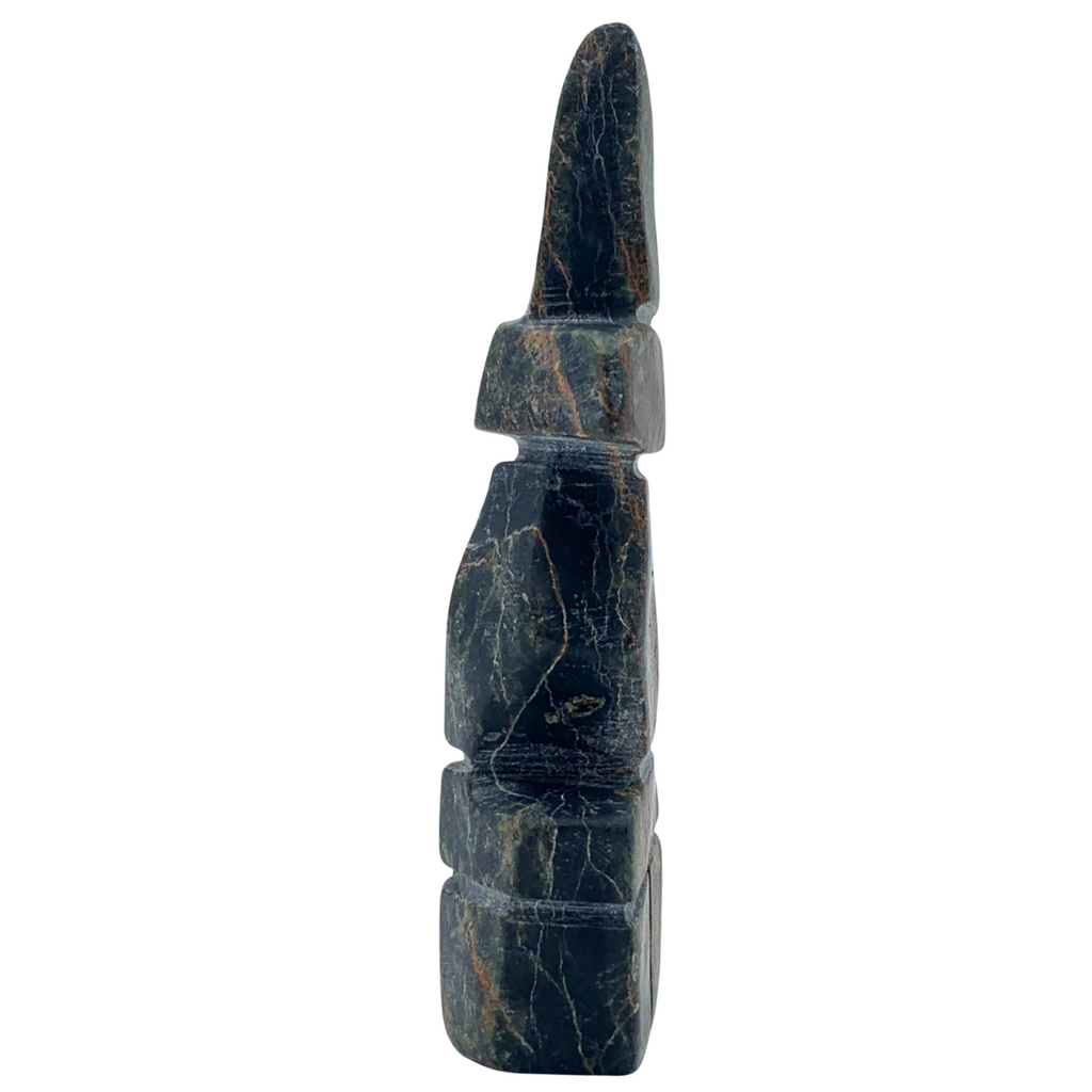 A human-shaped inukshuk sculpture, approximately 4 inches high. The stone is mottled black, brown and green soapstone.