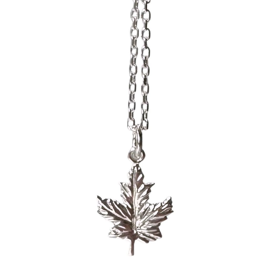 A small sterling silver maple leaf on a silver chain sits on a black background. The maple leaf charm is attached to the chain at its top point.