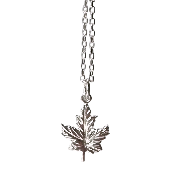 A small sterling silver maple leaf on a silver chain sits on a black background. The maple leaf charm is attached to the chain at its top point.