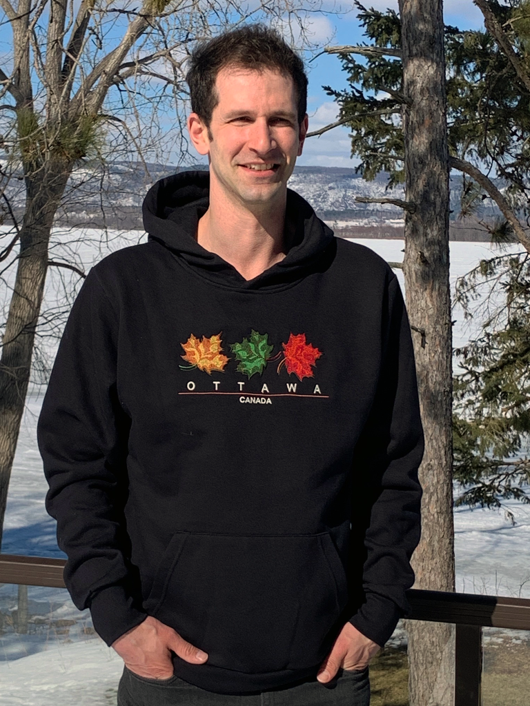 Cozy black pullover hoodie with yellow, green, and red embroidered maple leaves and the words OTTAWA, CANADA beneath.