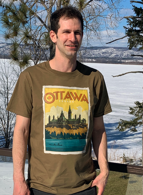 Cappucino unisex tee shirt with retro postage-stamp art showing the Parliament building with OTTAWA, CANADA in large letters above it. There is a maple leaf in the O.