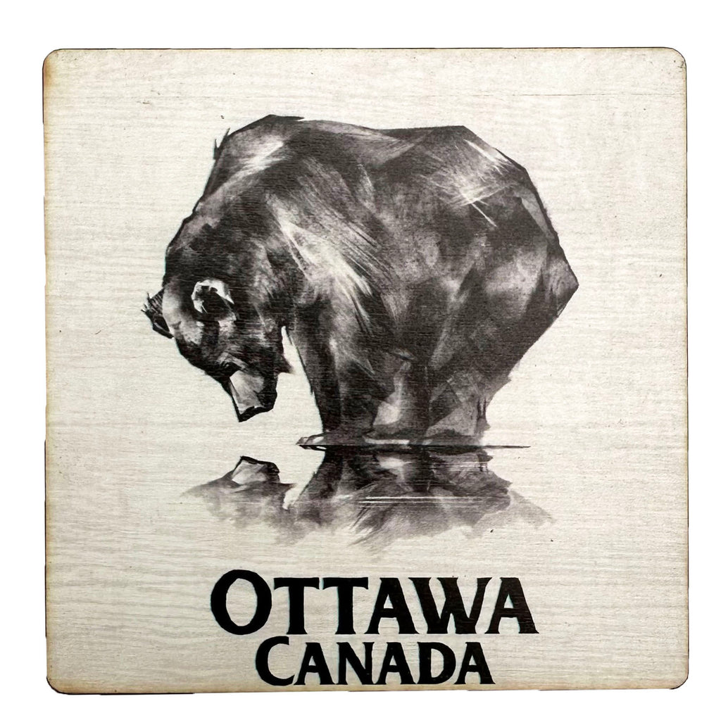 A square wooden coaster depicting a bear staring down at his reflection against a white background and the words" Ottawa, Canada" written on the bottom.