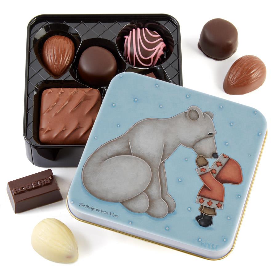 Delicious assorted chocolates in a stylish tin. On the cover of the tin, a small child in a red parka decorated with maple leaves speaks to a huge polar bear.