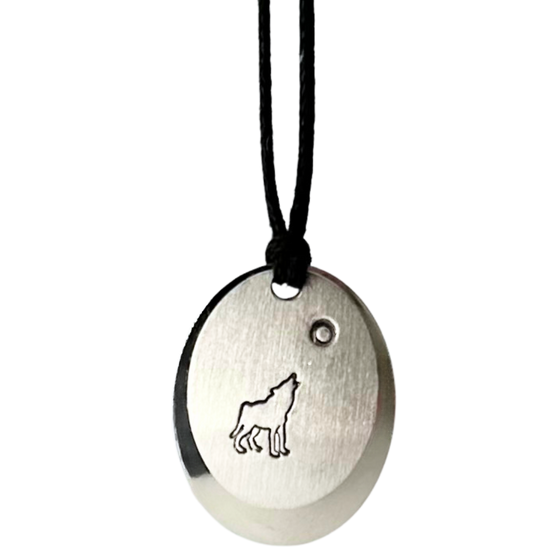 A necklace made of two layers of brushed and polished silver mounted on a leather cord. The base is an oval of bright polished silver. Over that is a smaller circle of brushed silver with a wolf howling at the moon etched into the centre.