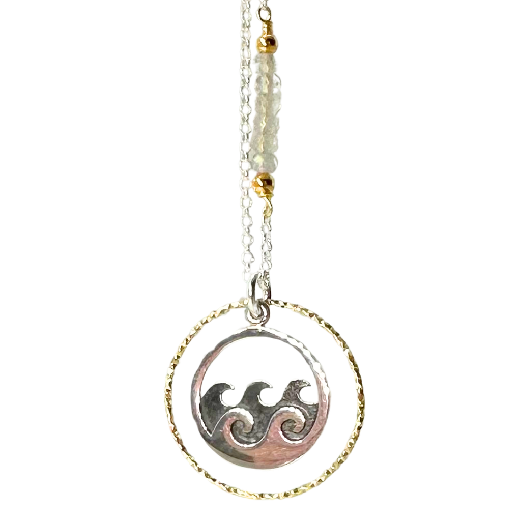 Silver chain with 5 coloured beads in middle of chain attached with gold chain links that look like flowers. Pendent is a gold ring that has triangle ridges. Inside gold ring is a silver ring with 2 silver waves and 4 grey waves behind them.