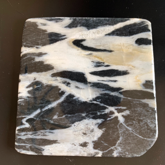 This coaster is made of a piece of canadian shield marble with mineral lines running through in unique colours, lines, and patterns. The coaster is finished with a clear coat, giving it a shiny finish. 